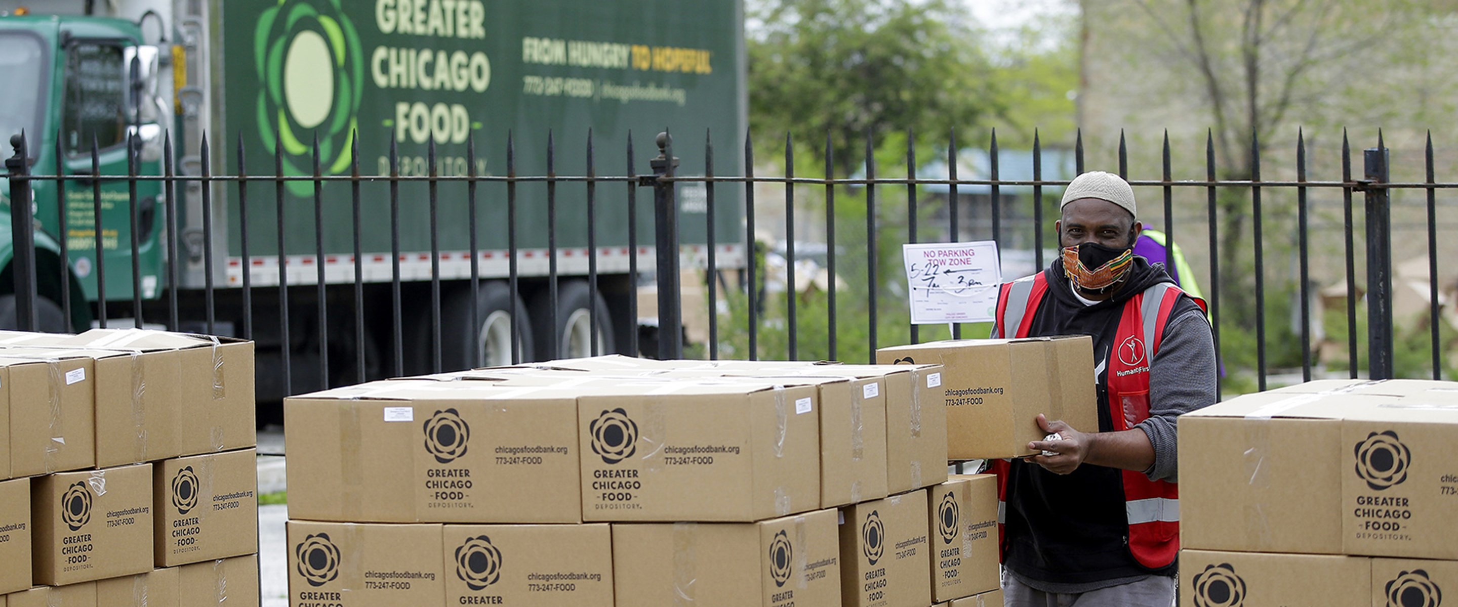 A worker stacking boxes next to a Greater Chicago Food Depository truck