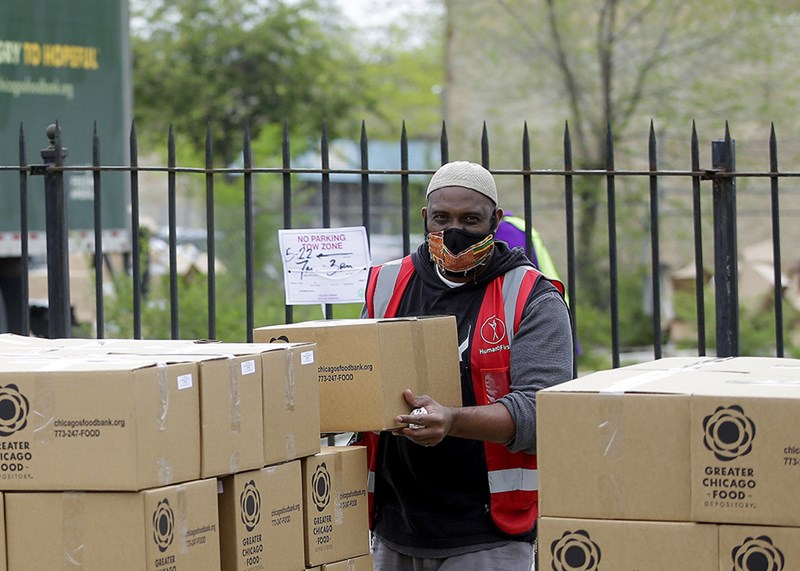 A worker stacking boxes next to a Greater Chicago Food Depository truck