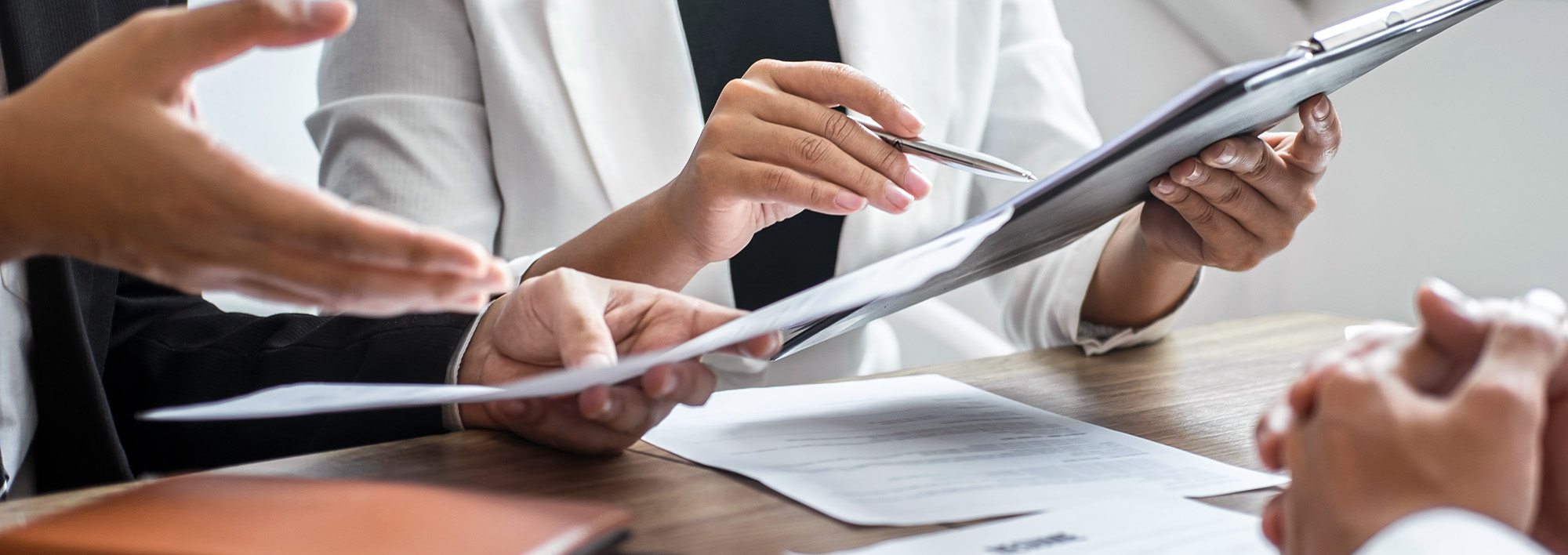 A hand on a calculator next to a laptop