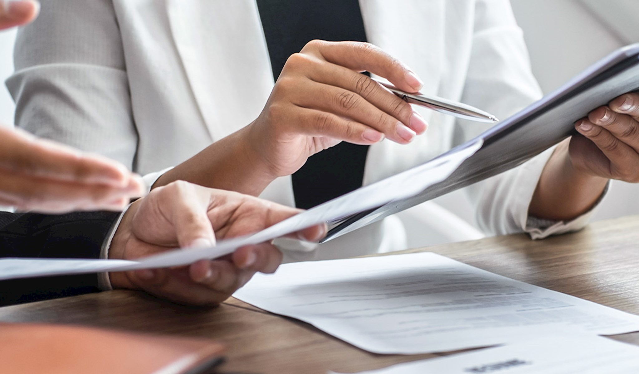 A hand on a calculator next to a laptop