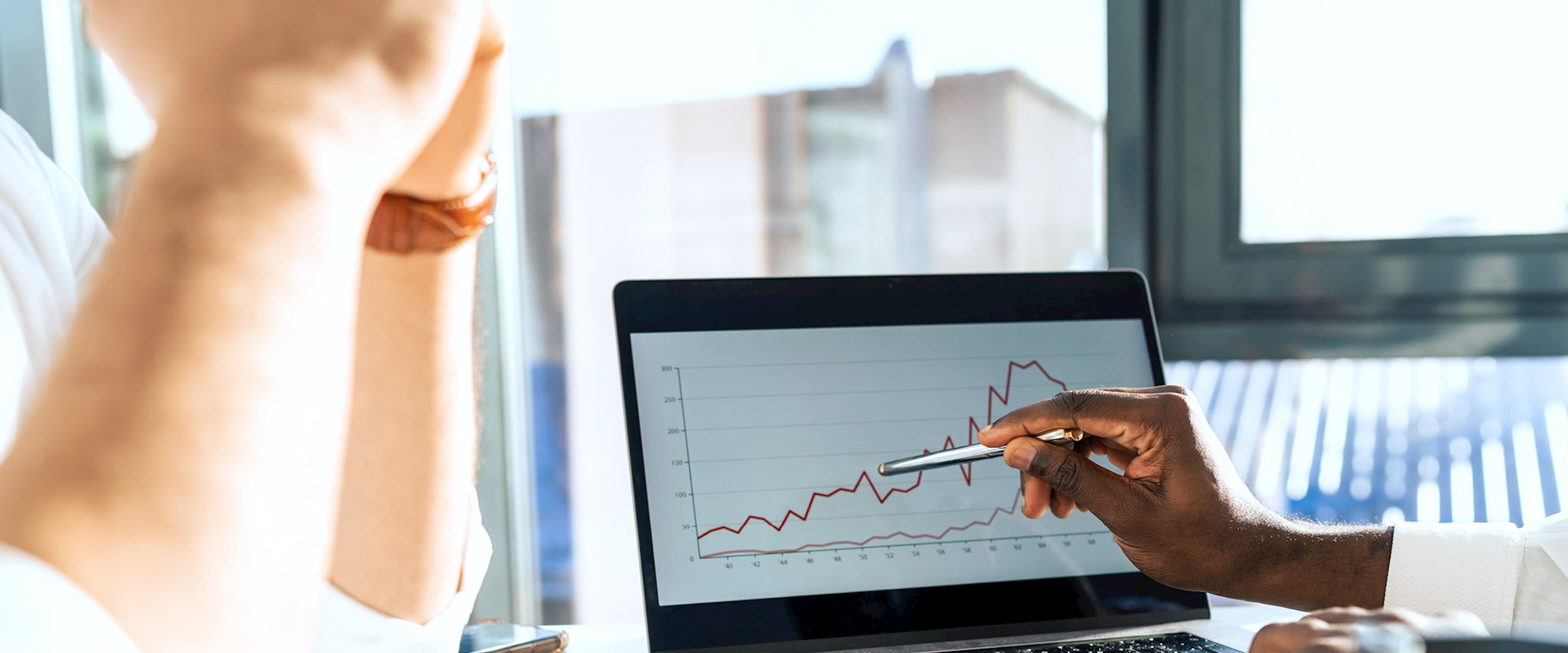 Hands pointing to a chart on a laptop