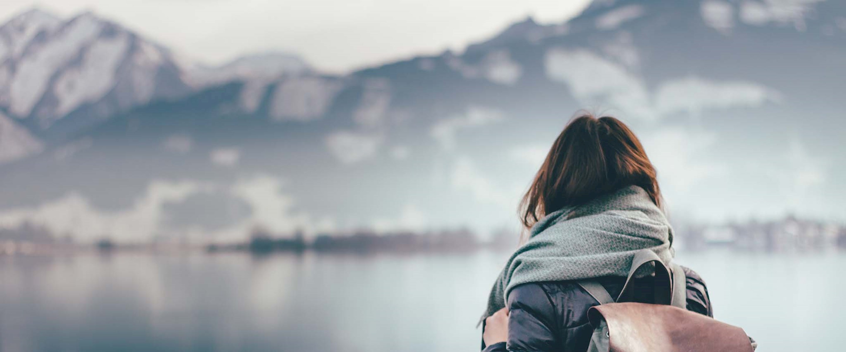 Girl with a backpack on looking at a lake