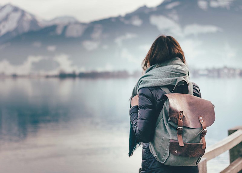 Girl with a backpack on looking at a lake