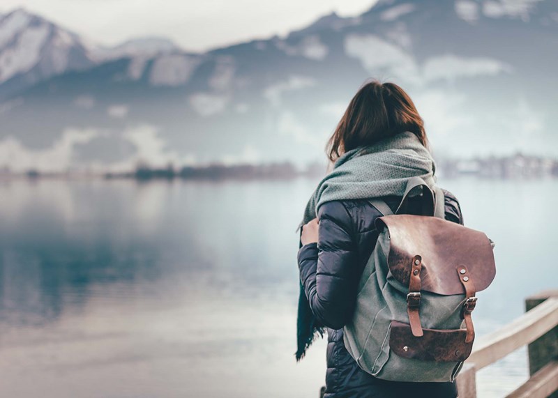 Girl with a backpack on looking at a lake