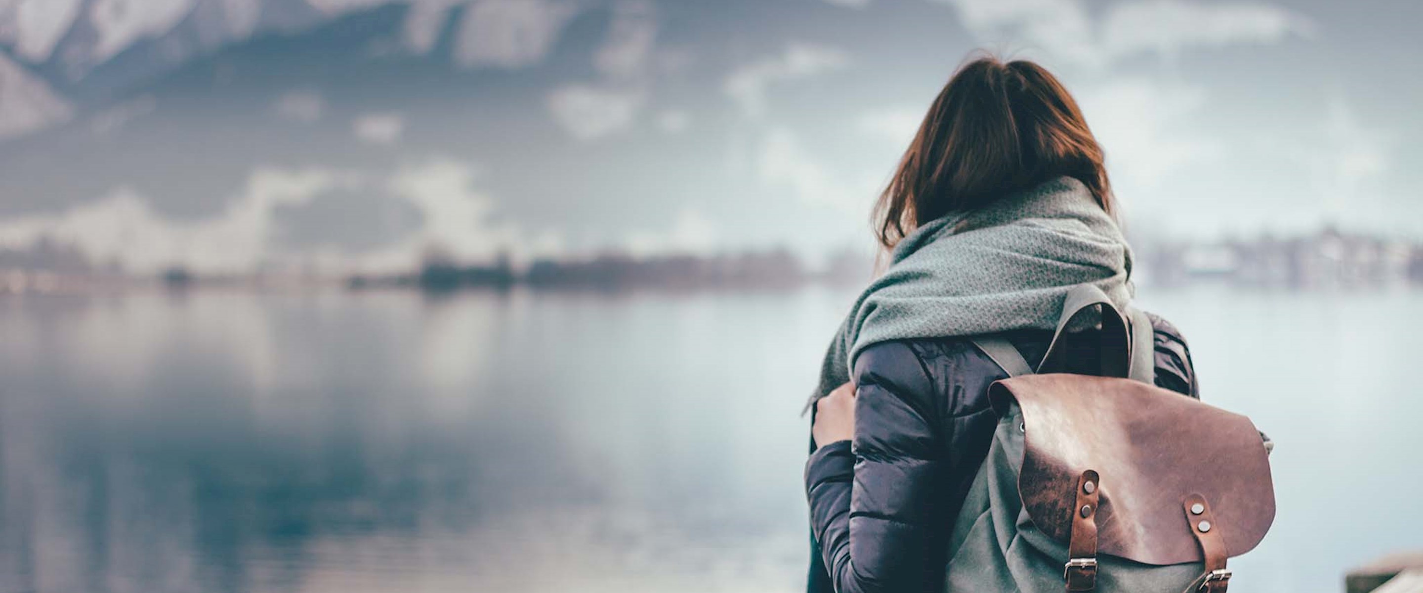 Girl with a backpack on looking at a lake
