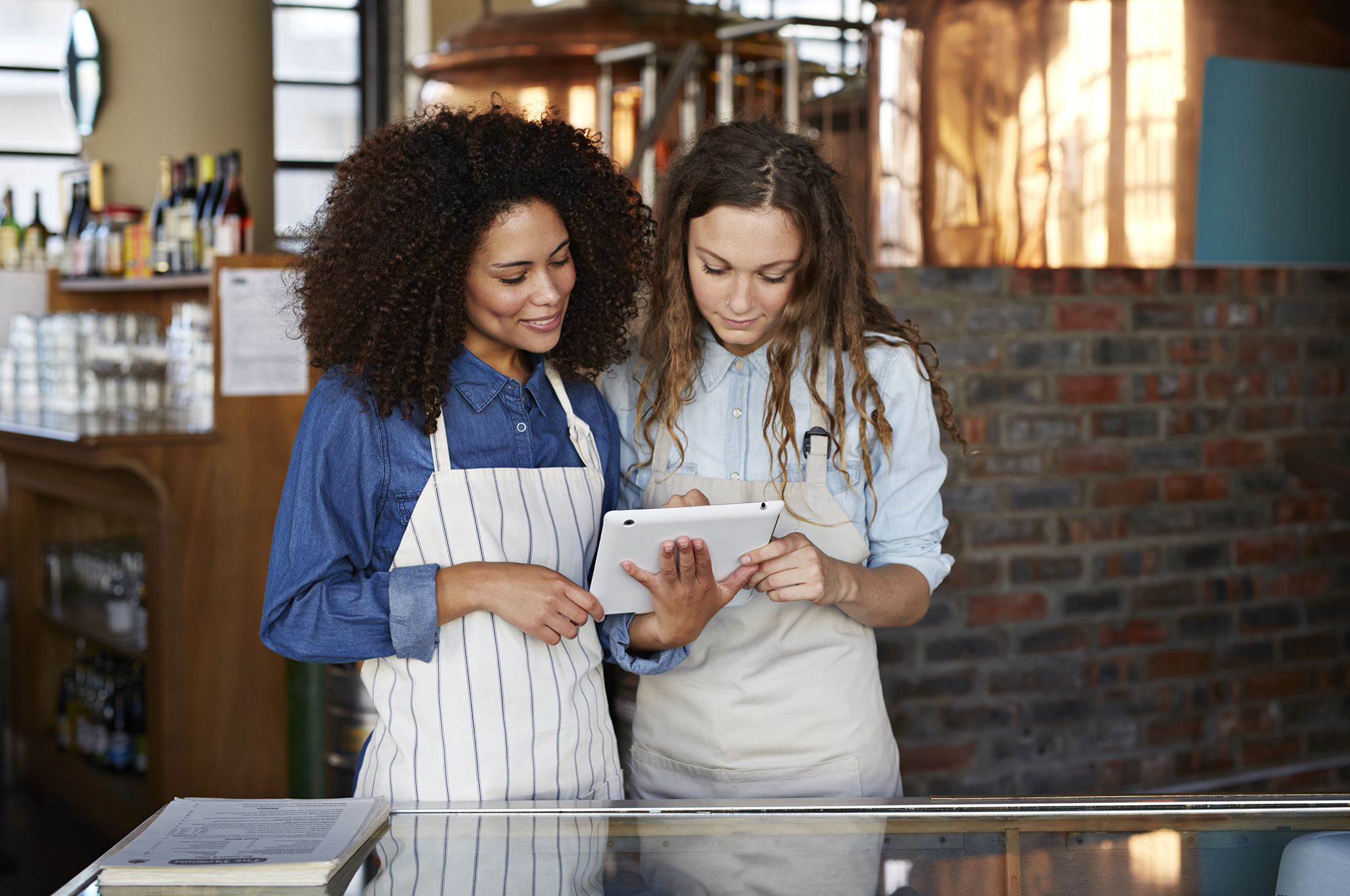 Two women in aprons looking at a tablet