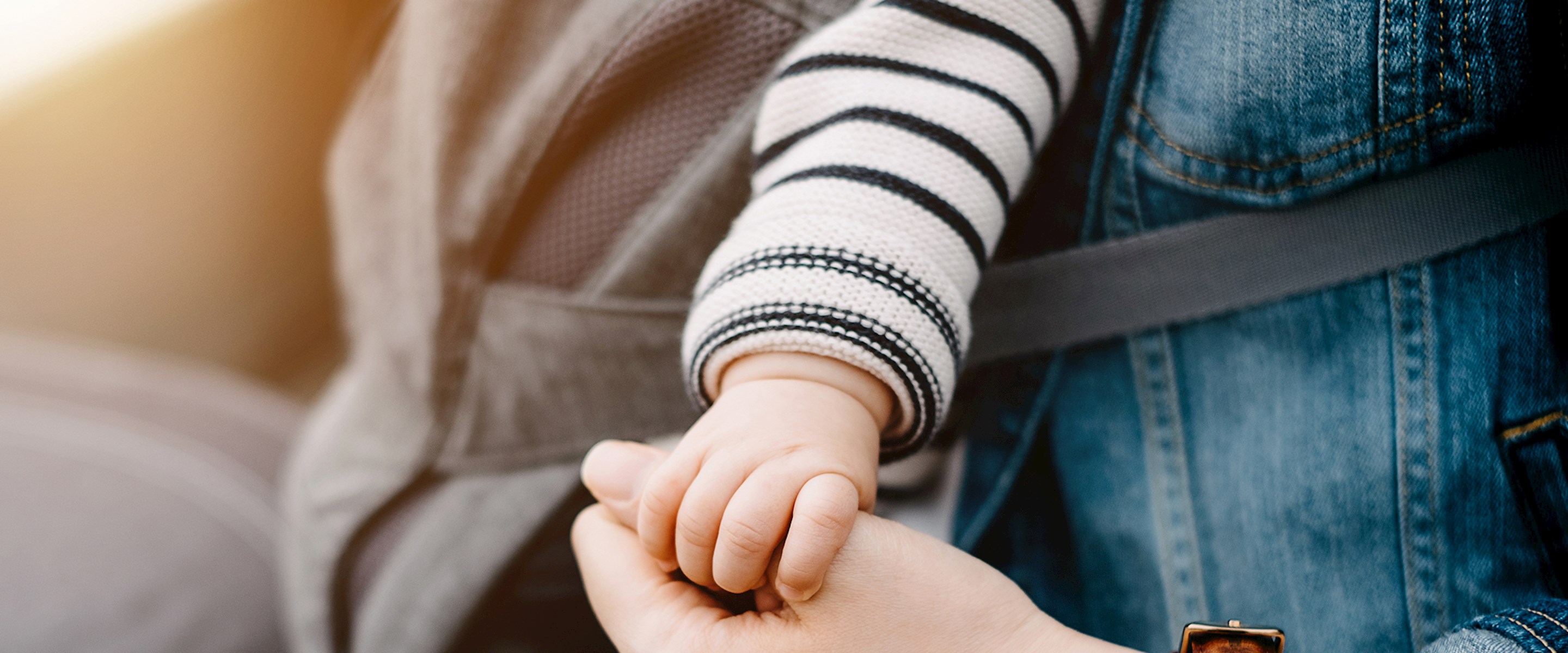 Closeup of a baby's hand holding an adult thumb