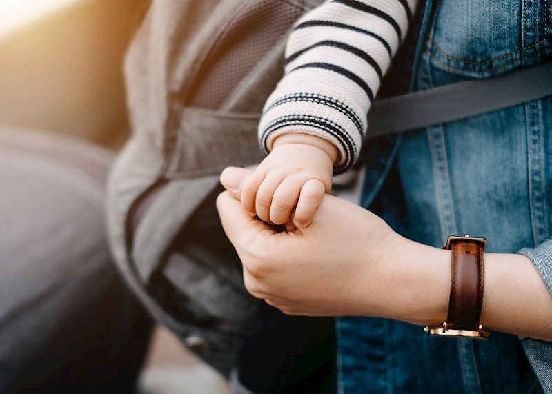 Closeup of a baby's hand holding an adult thumb