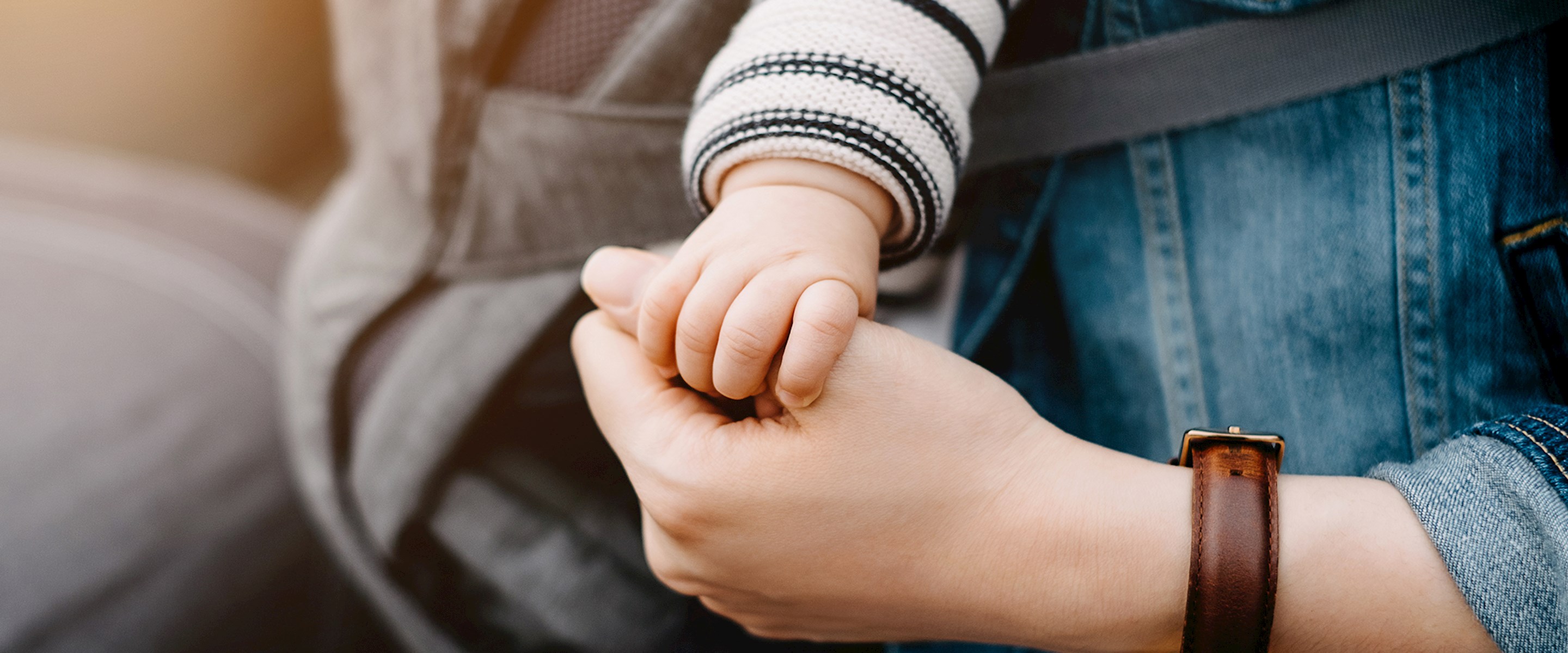 Closeup of a baby's hand holding an adult thumb