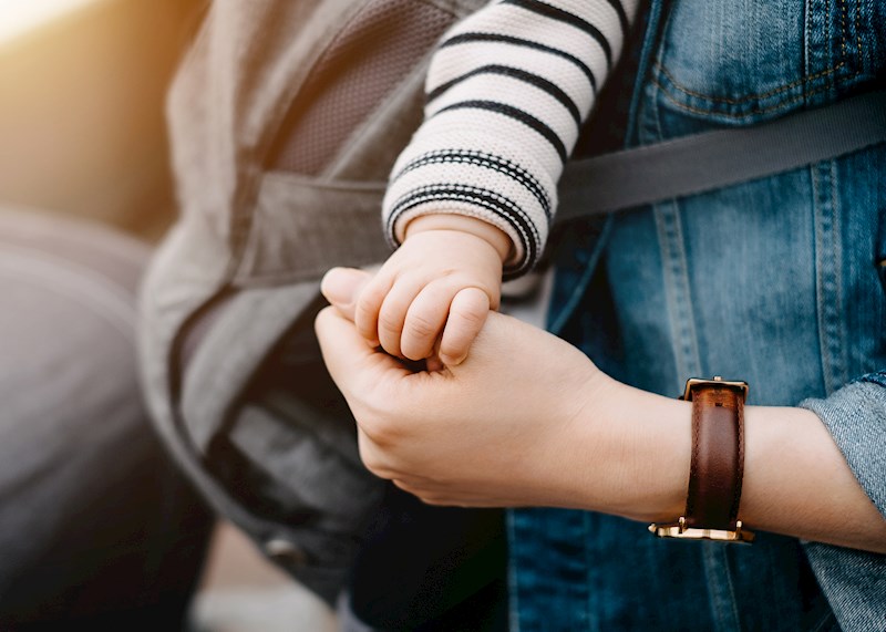 Closeup of a baby's hand holding an adult thumb