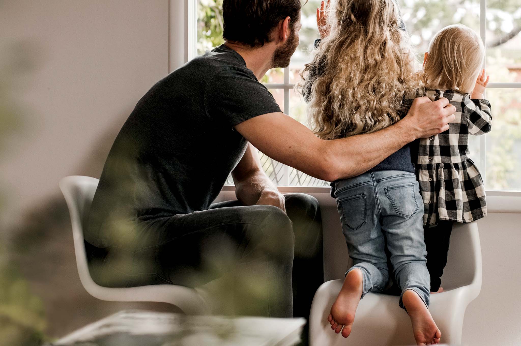 A man and two kids looking out a window