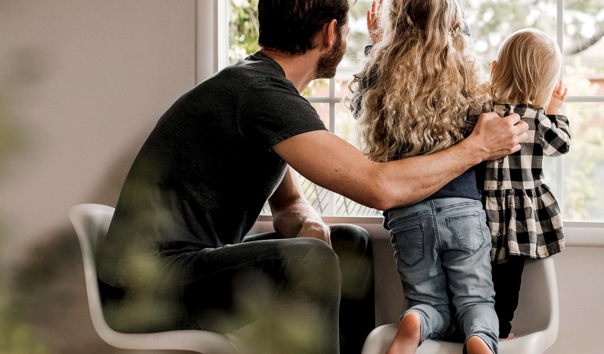 A man and two kids looking out a window