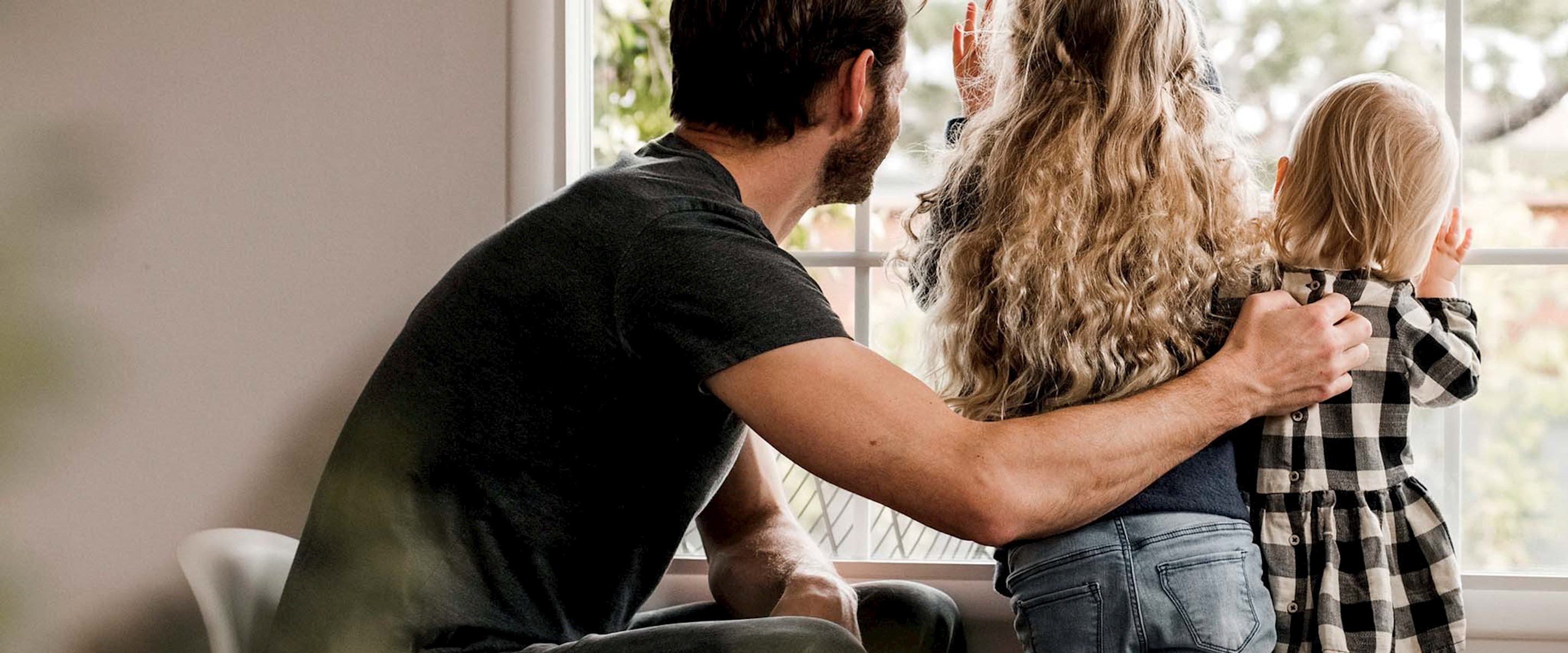 A man and two kids looking out a window