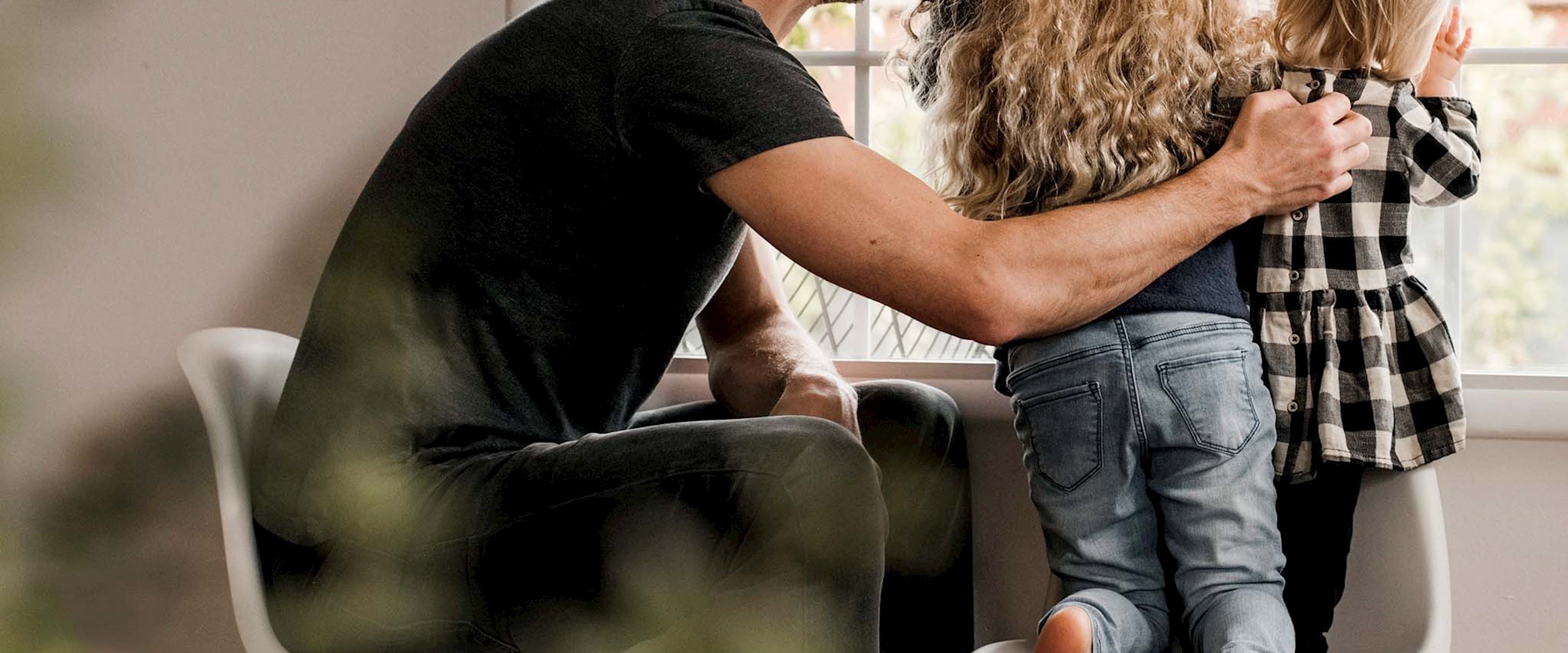 A man and two kids looking out a window