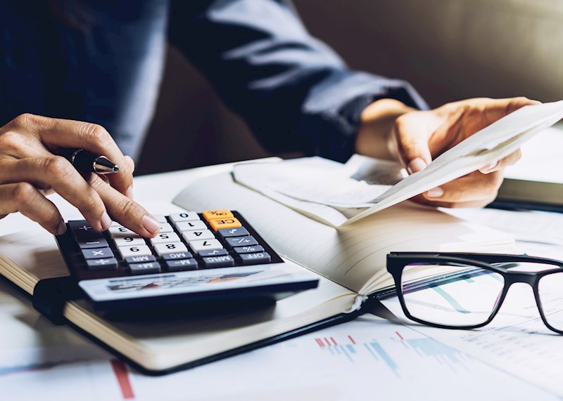 Hand on a calculator on a desk with papers