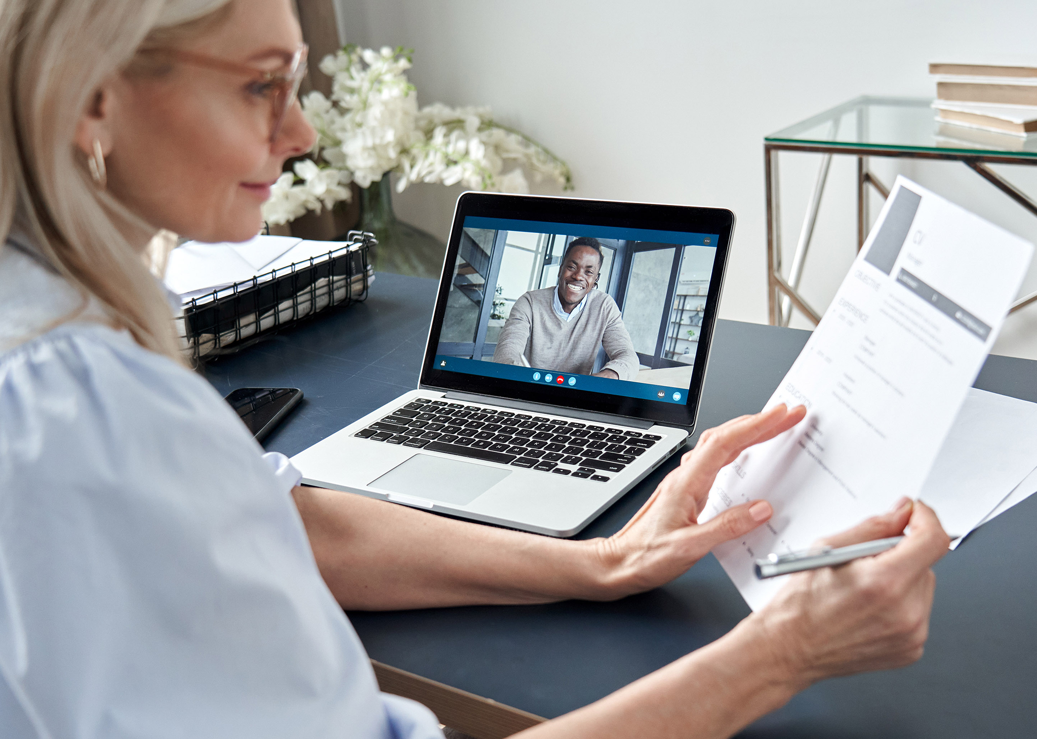 Woman at on a video conference call at a desk looking at papers