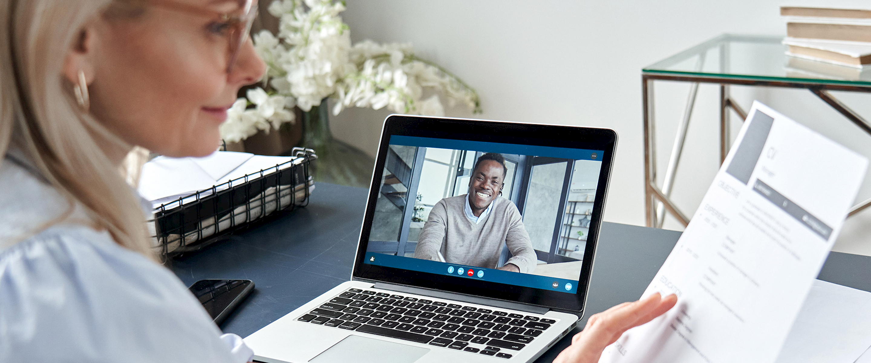 Woman at on a video conference call at a desk looking at papers