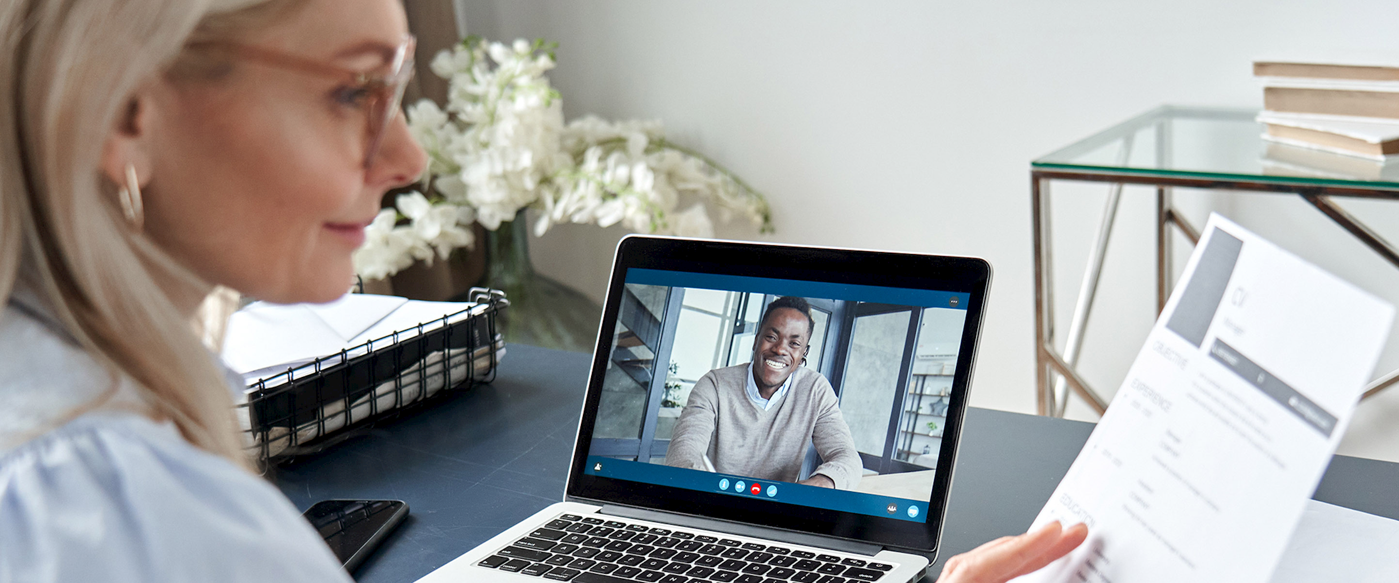 Woman at on a video conference call at a desk looking at papers