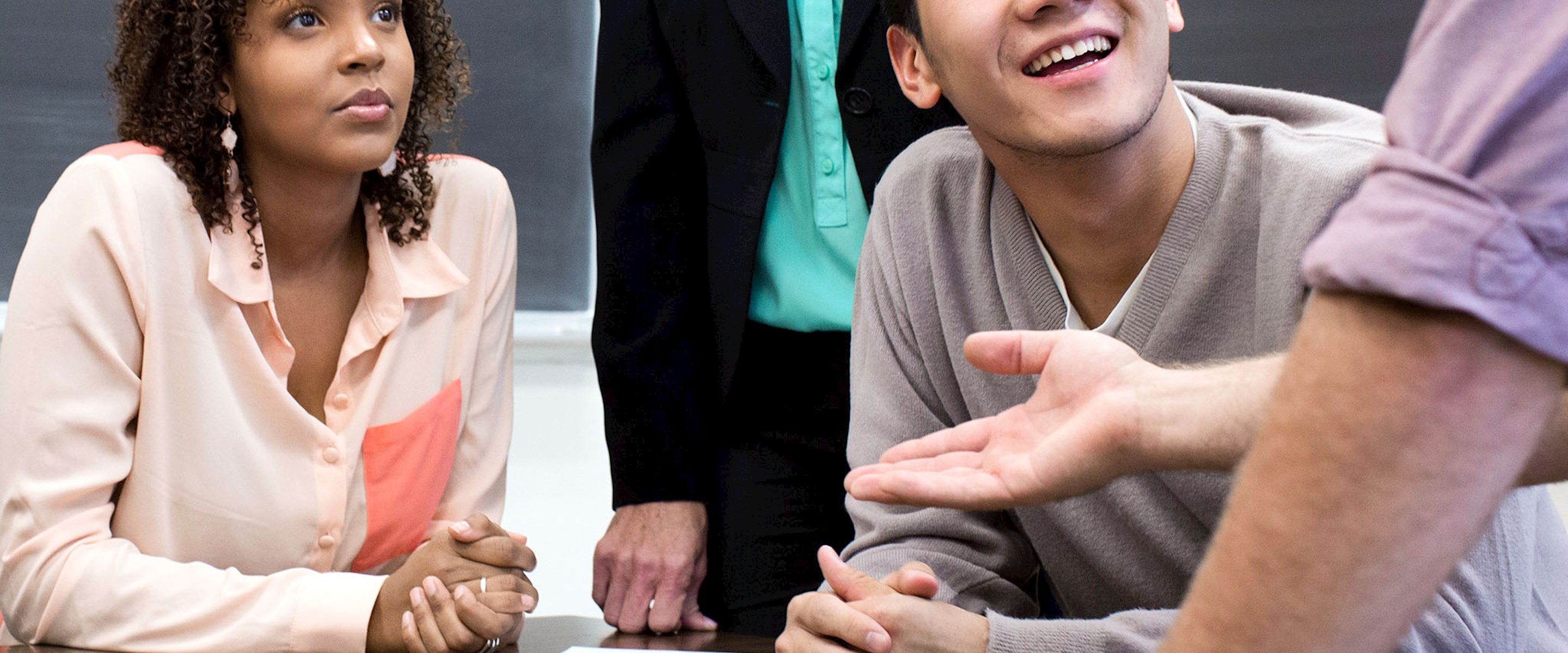 People at a table listening to someone standing