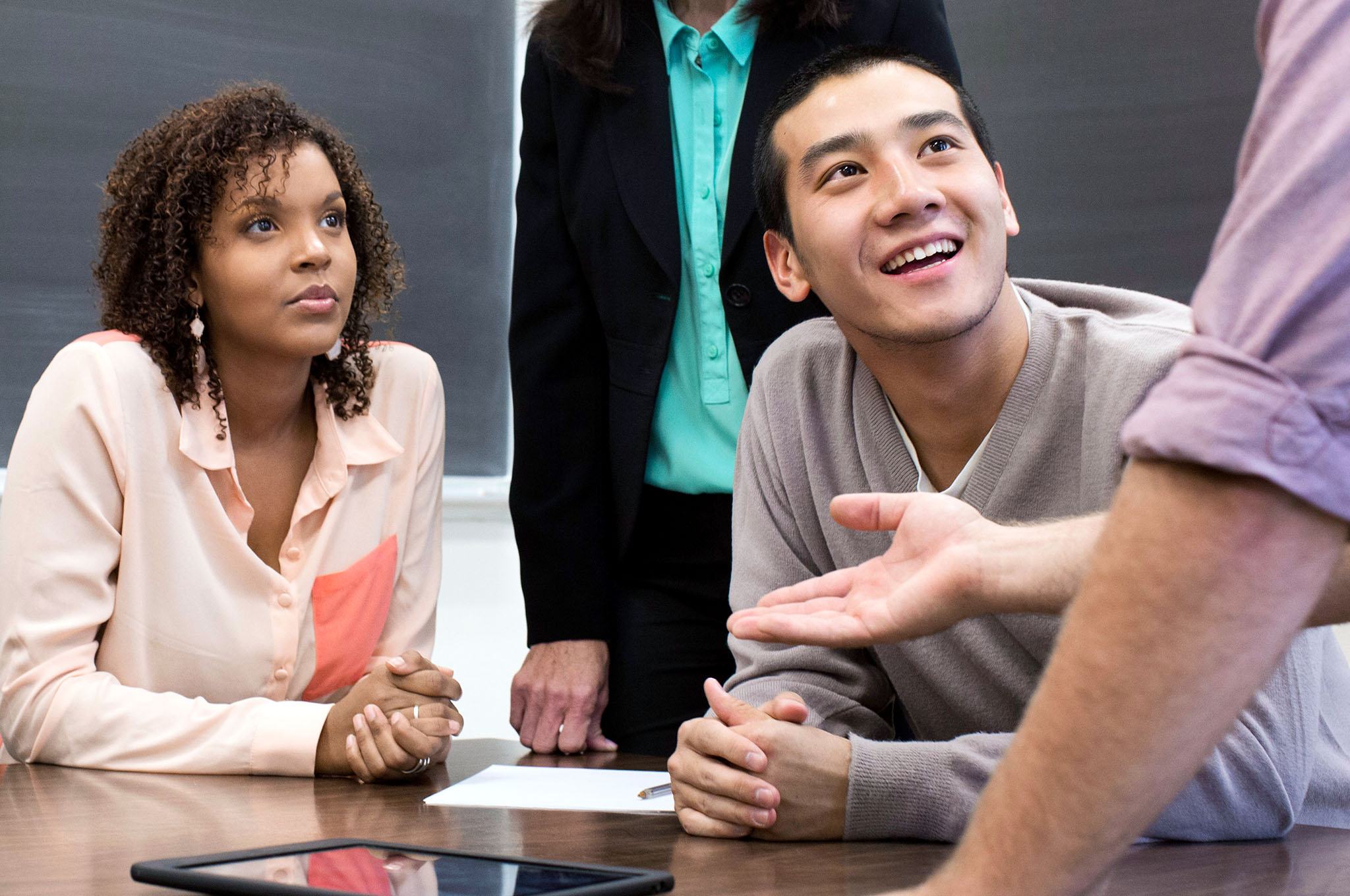 People at a table listening to someone standing