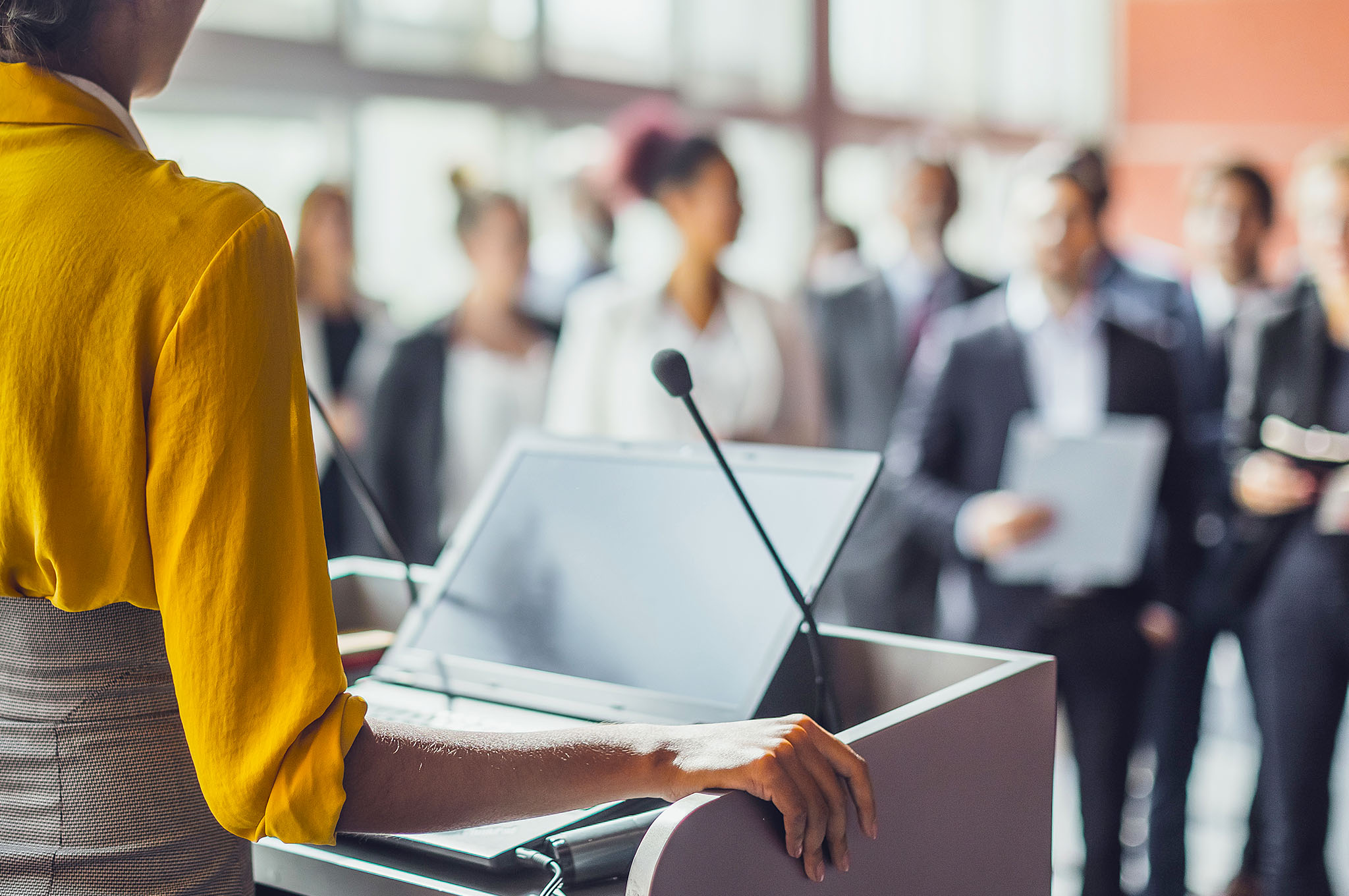 Woman at a dias talking to a crowd of prospective candidates
